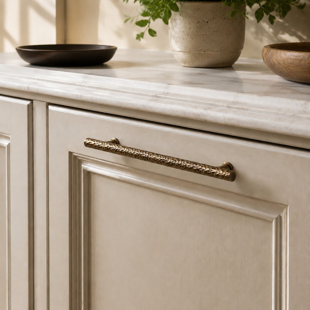 Hammered brass bar pull installed on a paneled cabinet drawer