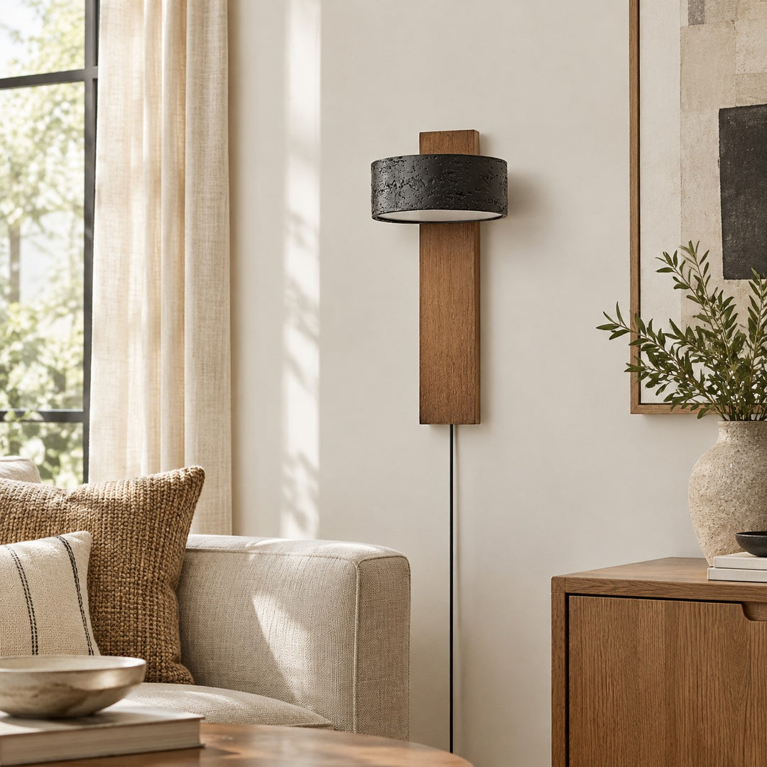 Walnut and black travertine wall sconce glowing beside a bed