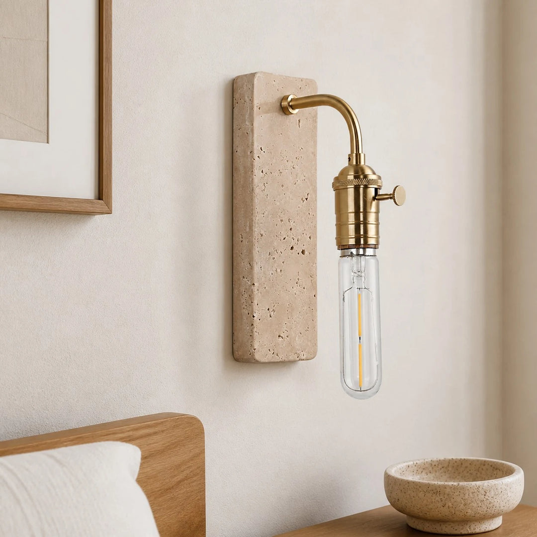 Gold travertine wall sconce installed beside a bed